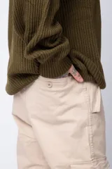 Pantalón cargo color beige con bolsillos laterales con solapa y botón. Corte ajustado.