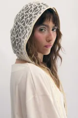 Capucha de encaje color crema con patrón circular, ribeteada en tono beige.