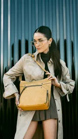 Cartera color mostaza de simil cuero, con apertura superior con cierre, bolsillo al frente con cierre y tachas metálicas, bolsillos verticales y bolsillo trasero con cierre. Incluye división al medio y bolsillos internos.