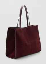 Bolso shopper de piel bovino en color borgoña, con acabado de serraje. Presenta dos asas de hombro y cierre principal con botón magnético. Incluye un bolsillo interior con cierre de cremallera.