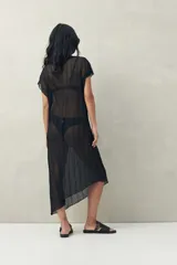 Top largo color blanco, confeccionado en tejido liviano con transparencia y caída fluida.