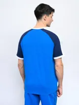 Remera de algodón azul con mangas ranglan azul marino y detalles en blanco en cuello y puños. Incluye logo de Umbro y escudo del Club Nacional de Football en el frente.