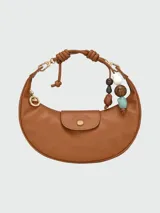 Bolso hobo de cuero color marrón, con cierre de solapa con botón a presión y correa corta para llevar al hombro. Incluye charm colgante con cuentas de madera y piedra.