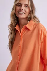 Camisa naranja fluida de manga corta con cuello clásico y cierre con botones.