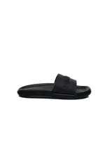 Ojotas negras con la marca Umbro en letras grandes en la tira.