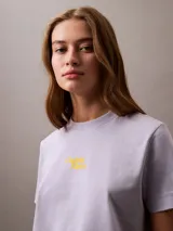 Remera de manga corta color lila de algodón con cuello redondo y logo Calvin Klein aterciopelado en color amarillo en el pecho.