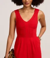 Mono largo rojo de sarga, con escote en V, sin mangas y detalle entrelazado en la cintura.