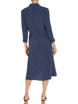 Vestido camisero midi azul marino con rayas verticales blancas, cuello camisero, cierre frontal con botones, mangas largas con puños abotonados y cinturón de lazo a juego.