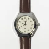 Reloj analógico con caja plateada, esfera blanca con números arábigos y correa marrón de cuero.