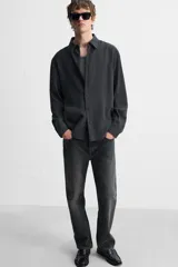 Camisa negra relaxed fit confeccionada en tejido fluido con mezcla de viscosa. Tiene cuello solapa, manga larga con puño abotonado y cierre frontal con botones.