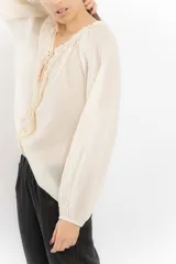 Blusa rosa de algodón con escote en V con cordones y detalle de volados.