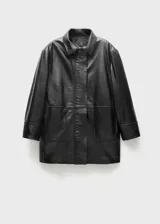 Abrigo negro oversize de cuero ovino con cuello alto y cierre frontal con cremallera y botones ocultos.