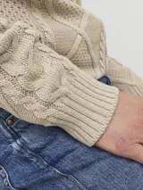 Sweater de punto color beige con cuello alto, cierre parcial con tres botones de madera y diseño con patrón de rombos y trenzas.
