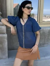 Camisa de gasa color gris oscuro, con mangas globo y una tira central vertical decorada con piedras azules.