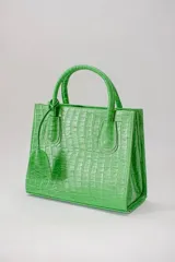 Cartera mediana color verde manzana con textura croco, confeccionada 100% en cuero. Tiene asa fija, correa regulable y desmontable.