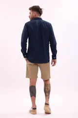 Camisa de manga larga color beige claro, de corte clásico y confeccionada en tejido texturizado.