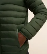 Campera puffer ultraligera color beige, con cuello alto, cierre por cremallera y bolsillos con cremallera. Incluye bolso de almacenamiento.