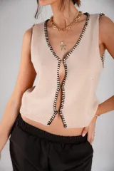 Chaleco tejido celeste con terminaciones en punto festón negro.