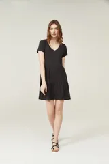 Vestido negro corto con cuello en V, manga corta y falda con volados.