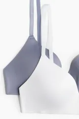 Pack de dos soutiens suaves de microfibra, uno blanco y otro gris azulado, con copas acolchadas que moldean y proporcionan buena sujeción. Tienen breteles ajustables y cierre de corchetes en la espalda.