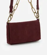 Cartera transversal pequeña color borgoña de gamuza sintética, con tapa y botón a presión, asa mediana de cadena dorada y asa larga fina desmontable.