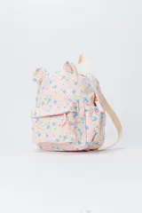 Mochila de tela color crudo con estampado floral en tonos pastel (azul, amarillo, rosa). Presenta un diseño acolchado (capitoné) y orejas en la parte superior, con tirantes de color beige claro.