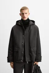Parka negra de corte regular, confeccionada en tejido técnico acolchado. Tiene cuello alto con capucha ajustable, mangas largas con puños ajustables, bolsillos con solapa en la cadera y un bolsillo interior. El cierre frontal es con cremallera oculta por solapa con botones a presión.