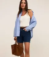 Short de jean azul oscuro, de tiro medio, con trabillas, bolsillos delanteros y traseros, cierre con botón y cremallera, y costuras contrastantes.