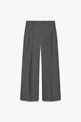 Pantalón gris de tiro alto con pinzas delanteras, bolsillos frontales y pernera ancha. Cierre frontal con cremallera, botón interior y gancho.