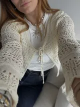 Saco calado color beige con mangas largas acampanadas y lazo de ajuste en el frente.