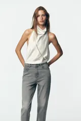 Pantalón de jean azul de tiro alto, corte mom fit, tobillero y con cinco bolsillos. Cierre frontal con cremallera y botón.