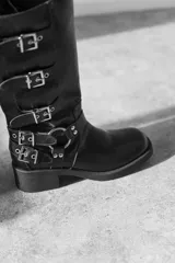 Bota de caña media color gris con múltiples hebillas metálicas.