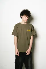 Remera verde oliva de corte regular fit, confeccionada en jersey de algodón. Presenta un pequeño logo bordado en el pecho y un estampado grande con el nombre de la marca en la espalda, ambos en color amarillo.