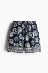 Short de tiro alto con estampado de motivos marinos en tonos azul y blanco. Presenta cintura elástica con cordón ajustable y bolsillos laterales.