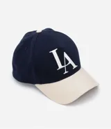 Gorra de sarga azul marino con visera curva color beige, bordado frontal con las letras LA en blanco y cierre ajustable en la parte posterior.