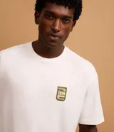 Remera blanca de corte relajado, cuello redondo y manga corta. Presenta un pequeño estampado con íconos de camping en el frente y la frase "We Don't Escape Reality" en la espalda.