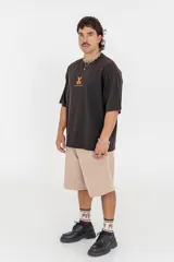Remera color beige con estampado de una pieza de ajedrez en color naranja en la espalda.