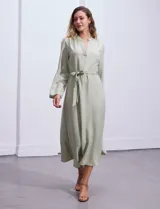 Vestido maxi color beige, con cuello mao, mangas 3/4 con presilla y lazo en la cintura.