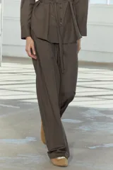 Pantalón de tiro medio color marrón, con cintura elástica ajustable con cordones, bolsillos delanteros y traseros, raya planchada y pierna recta.