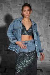 Campera de jean celeste con apliques de strass y cadenas en hombros y bolsillos.