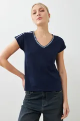 Remera blanca de algodón con escote en V y bordado en el borde. De corte recto y mangas cortas.