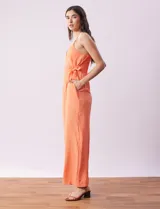 Enterito de crepe color naranja, marca Luxology. Escote en V cruzado, cintura elastizada con lazo de ajuste, espalda en punto smock y breteles de cadena.
