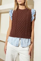 Chaleco marrón de punto con diseño trenzado, cuello redondo y sisas con volantes celestes.