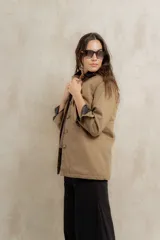 Campera color beige con cuello de corderito negro, cierre con botones, bolsillos laterales y puños con detalle de cuero sintético negro.