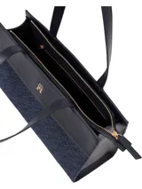 Bolso tipo tote de poliéster reciclado con diseño jacquard con monograma TH en azul marino. Tiene dos asas superiores de cuero sintético negro y logo metálico dorado de Tommy Hilfiger en el frente.