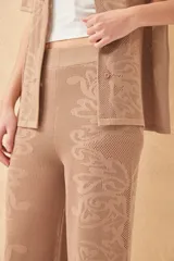 Pantalón tejido color crudo, con diseño calado de corazones y arabescos. Corte palazzo.