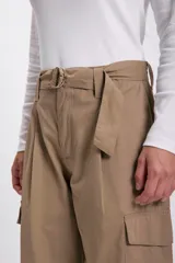 Pantalón cargo color beige con cinturón con hebilla metálica, bolsillos laterales con solapa y ajuste con hebilla en los tobillos.