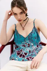 Top con estampado floral en tonos celeste, lila y blanco, con escote en V, breteles trenzados y elástico en la espalda.