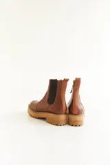 Botas cortas de cuero color marrón y beige, con elástico lateral y suela track color negro.