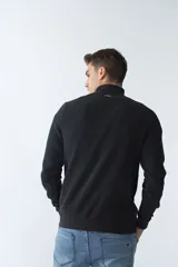 Buzo negro de algodón con cuello alto y medio cierre. Tiene logo bordado en el pecho y puños en las mangas.